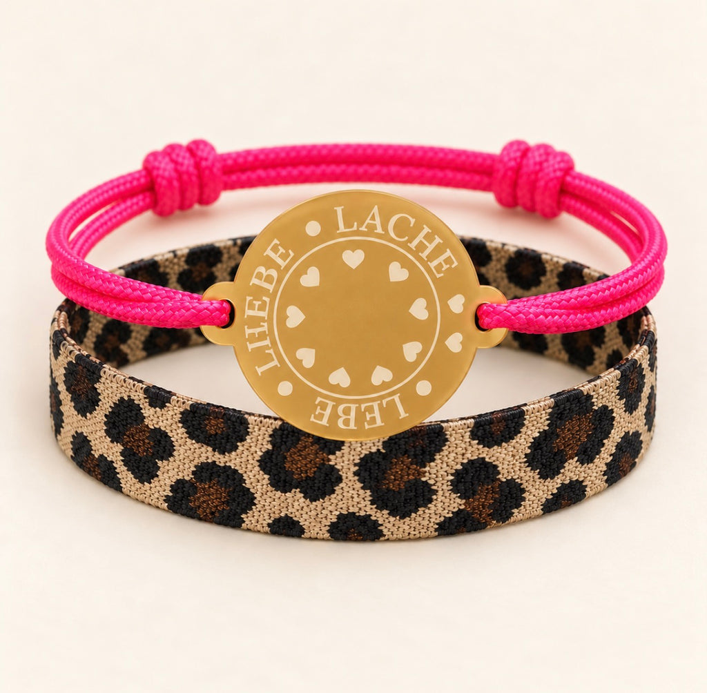 Happycoin Armband-Set mit pinkem Band, goldfarbenem Coin mit der Aufschrift Lebe • Liebe • Lache und textilem Leo-Armband.“

