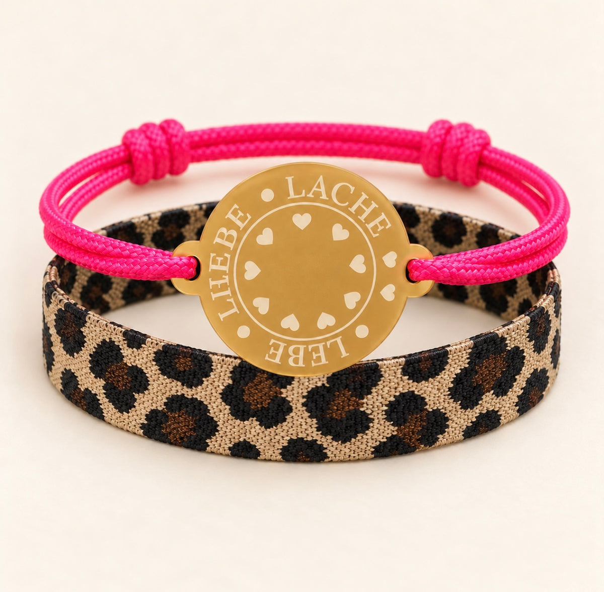 Happycoin Armband-Set mit pinkem Band, goldfarbenem Coin mit der Aufschrift Lebe • Liebe • Lache und textilem Leo-Armband.“

